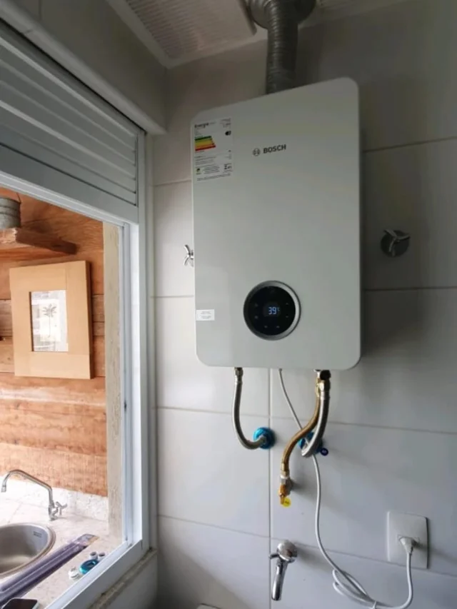 Aquecedor a gás Bosch digital instalado pela Configás em área de serviço, com chaminé, ligações flexíveis de água e gás e tomada dedicada