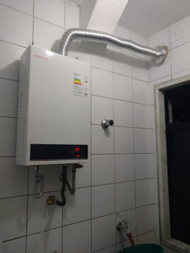 Aquecedor a gás Cumulus digital instalado pela Configás, com chaminé até a saída na parede e ligações de água e gás