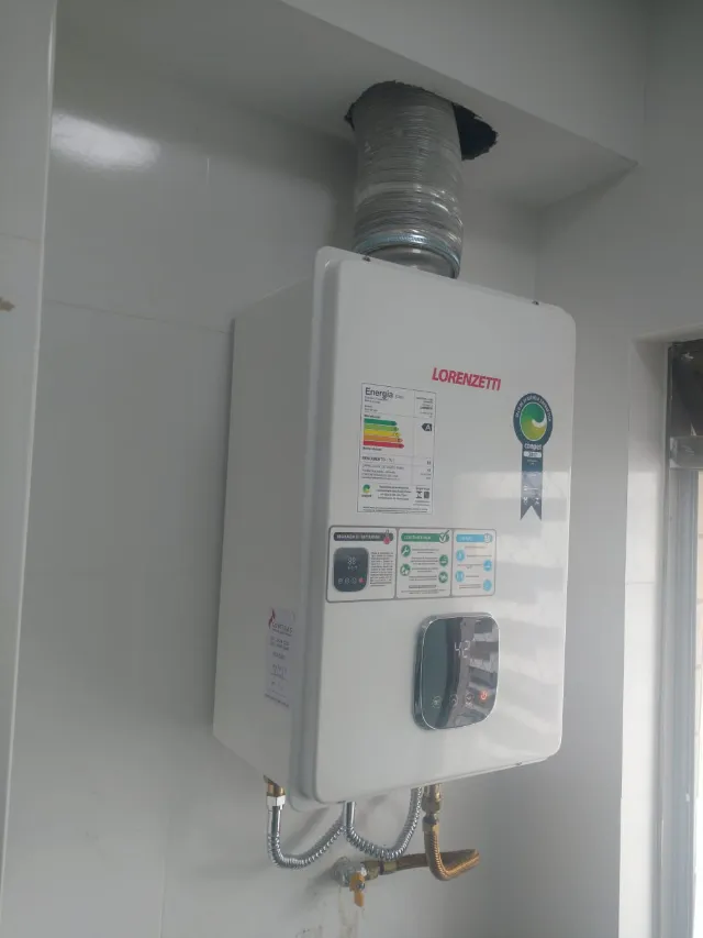 Aquecedor a gás Lorenzetti digital instalado pela Configás em área de serviço, com chaminé e etiqueta de revisão