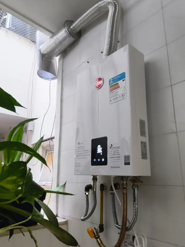 Aquecedor a gás Rheem de 15 litros digital instalado com chaminé até a janela e etiqueta de revisão da Configás