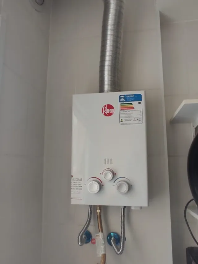 Aquecedor a gás Rheem mecânico instalado pela Configás, com chaminé e ligações flexíveis de água e gás
