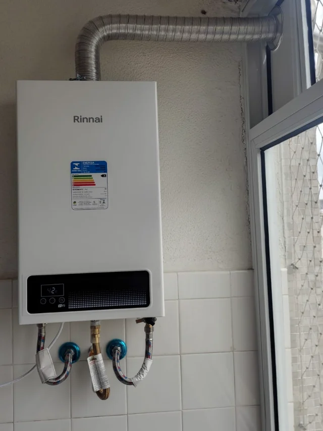 Aquecedor a gás Rinnai REU E-15 digital instalado pela Configás, com o painel marcando 42 °C e chaminé até a janela