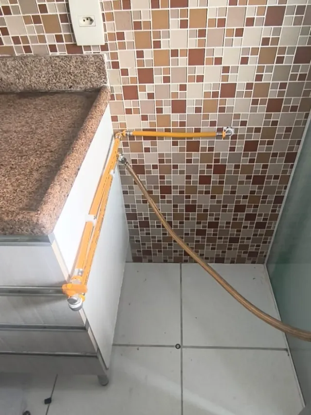 Tubulação de gás em multicamada amarela aparente na cozinha, com registro e mangueira metálica para o fogão